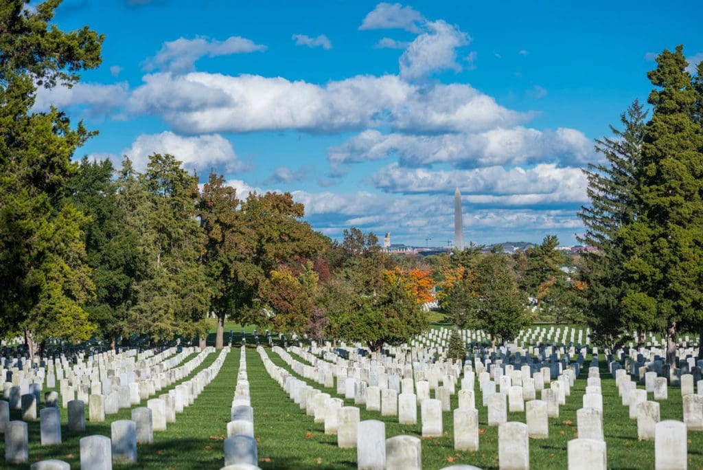 A view of Arlington National Cemetery, with rows of white tombstones, on a sunny day.