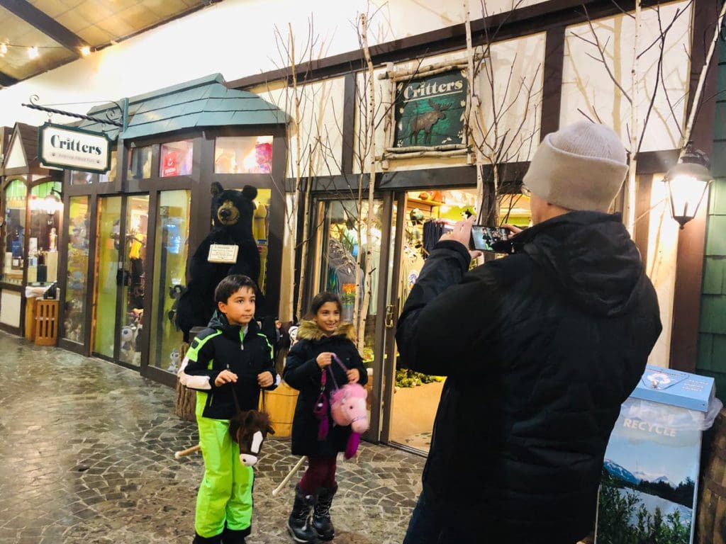 A dad takes a picture of his two children on his cellphone, while exploring the town of Lake Placid.