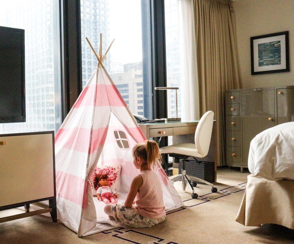 A young girl plays in a cozy, pink in-room tent at The Langham, Chicago.