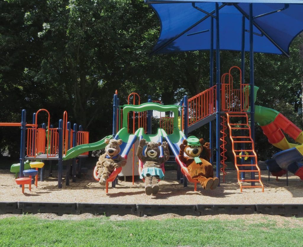 Three Yogi Bear-inspired mascots hang out at a on-sight playground at Jellystone Park in Lodi, California, one of the best themed hotels on the West Coast for families