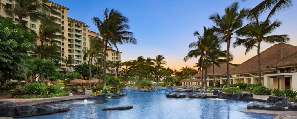 The resort grounds at Marriott's Ko Olina Beach Club, featuring the pool, tall resort buildings, and palm trees at one of the Best Marriott Properties in the U.S. for a Family Vacation.