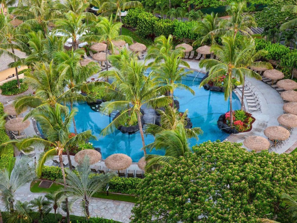 An aerial view of the pool, surrounding cabanas, and palm trees at Marriott's Ko Olina Beach Club, one of the Best Marriott Properties in the U.S. for a Family Vacation.