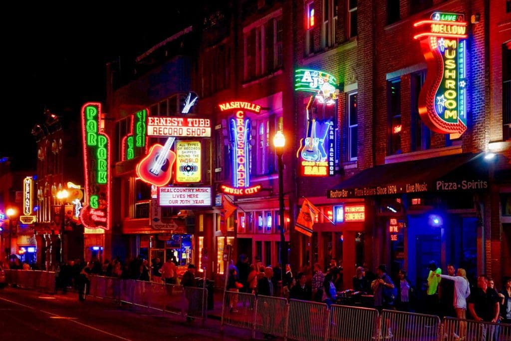 A view of a street in Nashville, one of the best places to travel with your mom, featuring rows of neon lights announcing bar and restaurant locations.