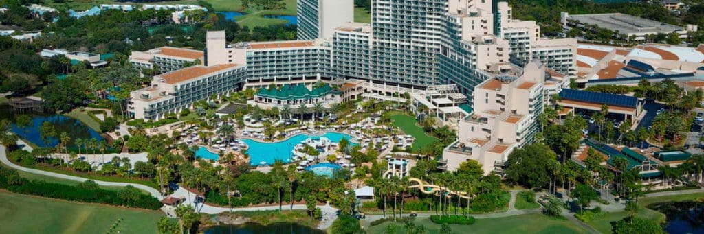 An aerial view of the resort and grounds at Orlando World Center Marriott, featuring the pool, buildings, and palm trees at one of the Best Marriott Properties in the U.S. for a Family Vacation.