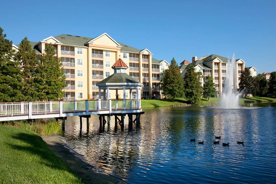 A view of the pond, fountain, and boardwalk at Sheraton Vistana Resort Villas, with resort buildings in the distance at one of the Best Marriott Properties in the U.S. for a Family Vacation.