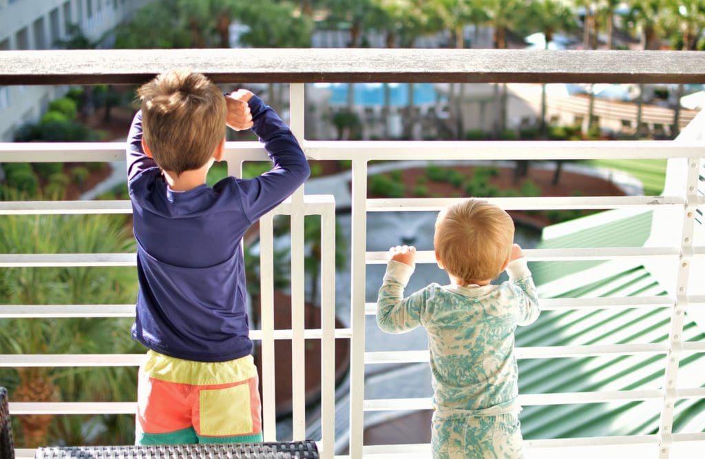Two brothers stand near each other looking over a balcony at Photo Courtesy: Marriott Hotels & Resorts.