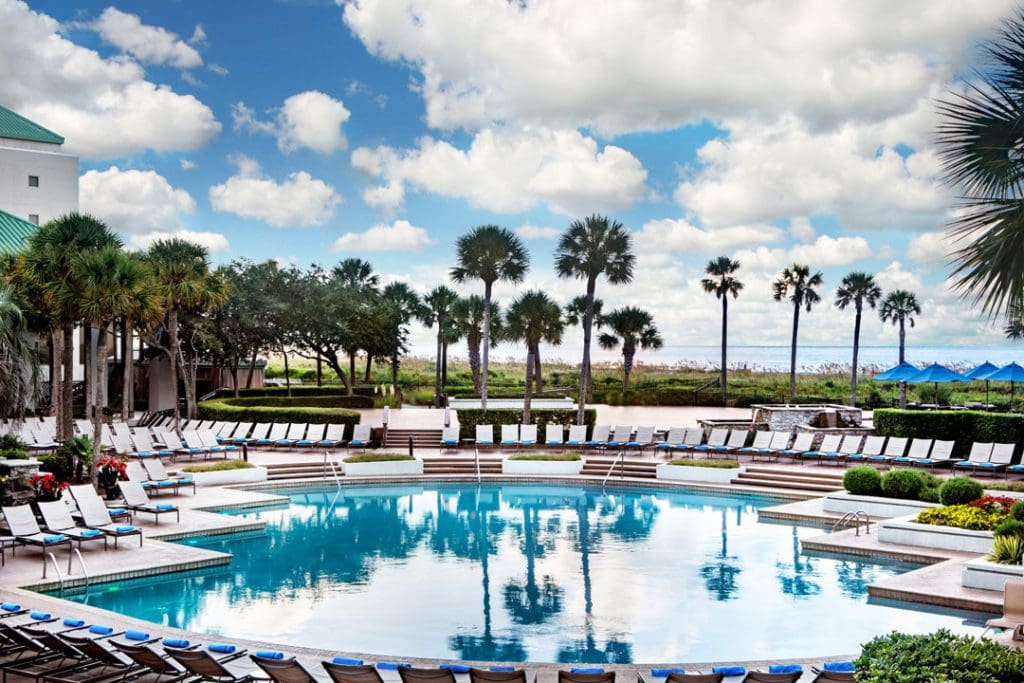 The pool and surrounding pool deck at Marriott Hotels & Resorts, with a variety of palm trees in the distance at one of the Best Marriott Properties in the U.S. for a Family Vacation.