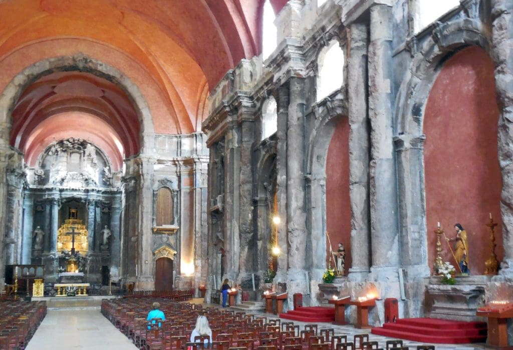 Inside the Church of St. Dominic, featuring historic columns, an alter, and a few people sitting in the pews.