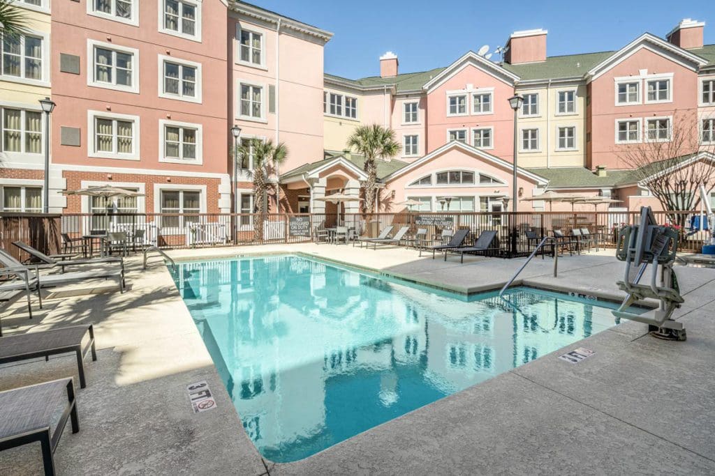 The outdoor pool at Residence Inn by Marriott Charleston Riverview, with large, pink-hued hotel buildings behind it.