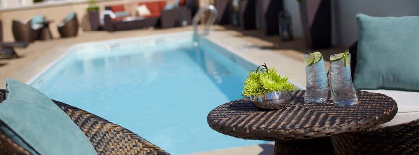 A close up of a table holding drinks with the outdoor pool behind it at The Renaissance Charleston Historic District Hotel.