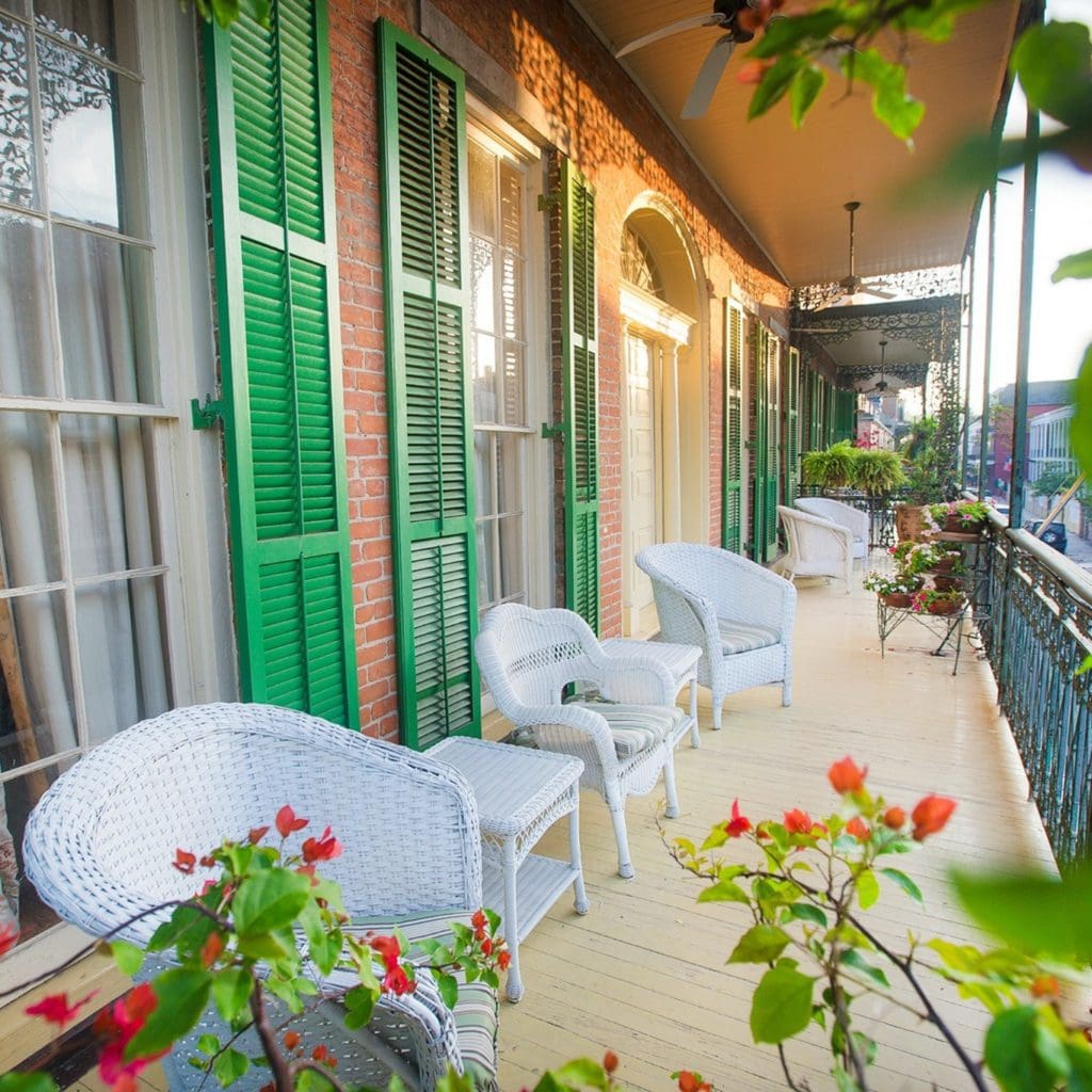 A balcony, lined with white whicker chairs and lovely flowers at Soniat House Hotel.