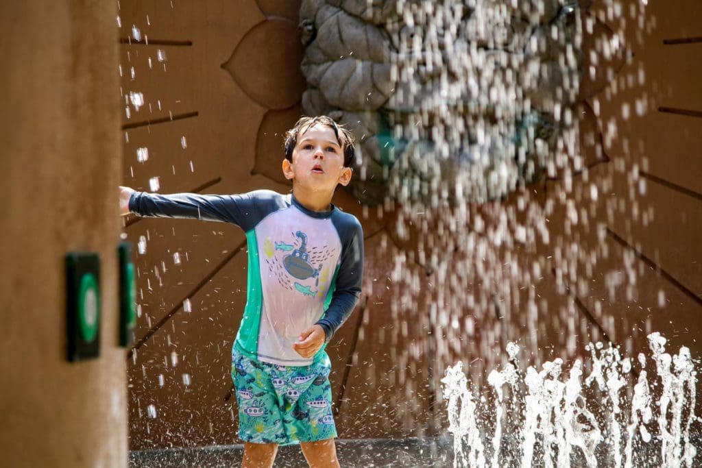 A young boy splashes in the water at the splash zone at the Atlanta Botanical Garden.