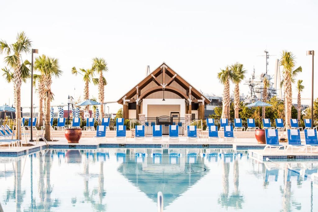 The outdoor pool at The Beach Club at Charleston Harbor Resort and Marina, flanked by poolside loungers and palm trees.