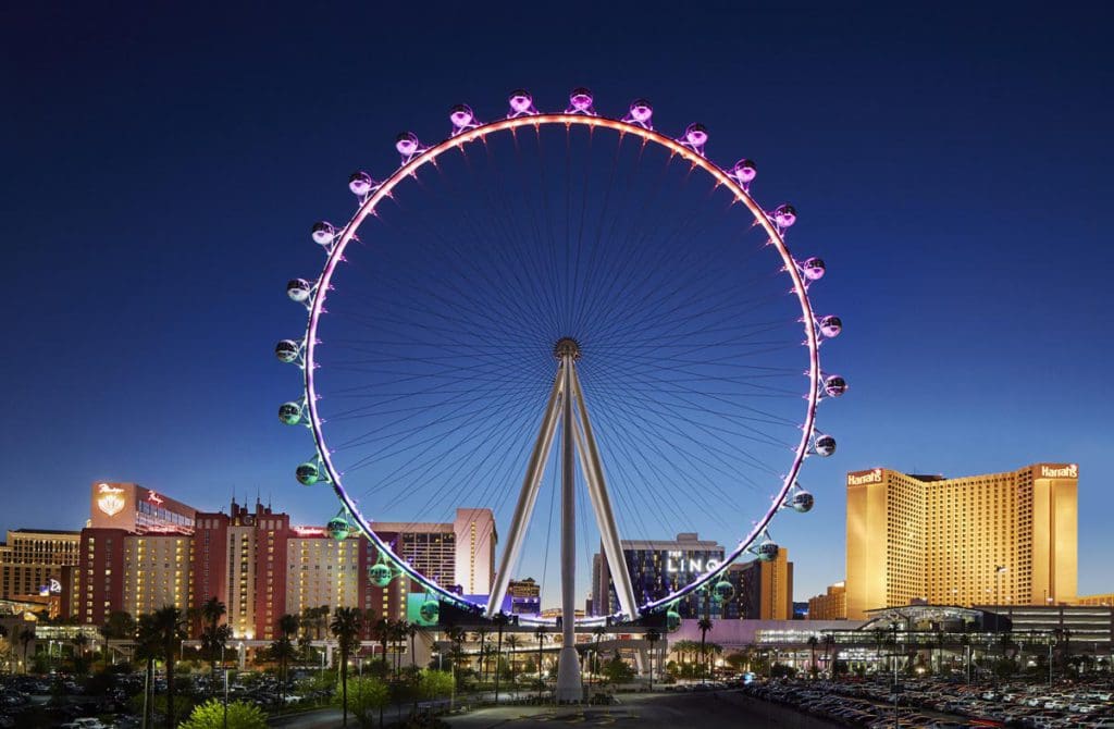 A view of the High Roller Las Vegas Strip Observation Wheel lit up purple at night surrounded by the Las Vegas skyline.