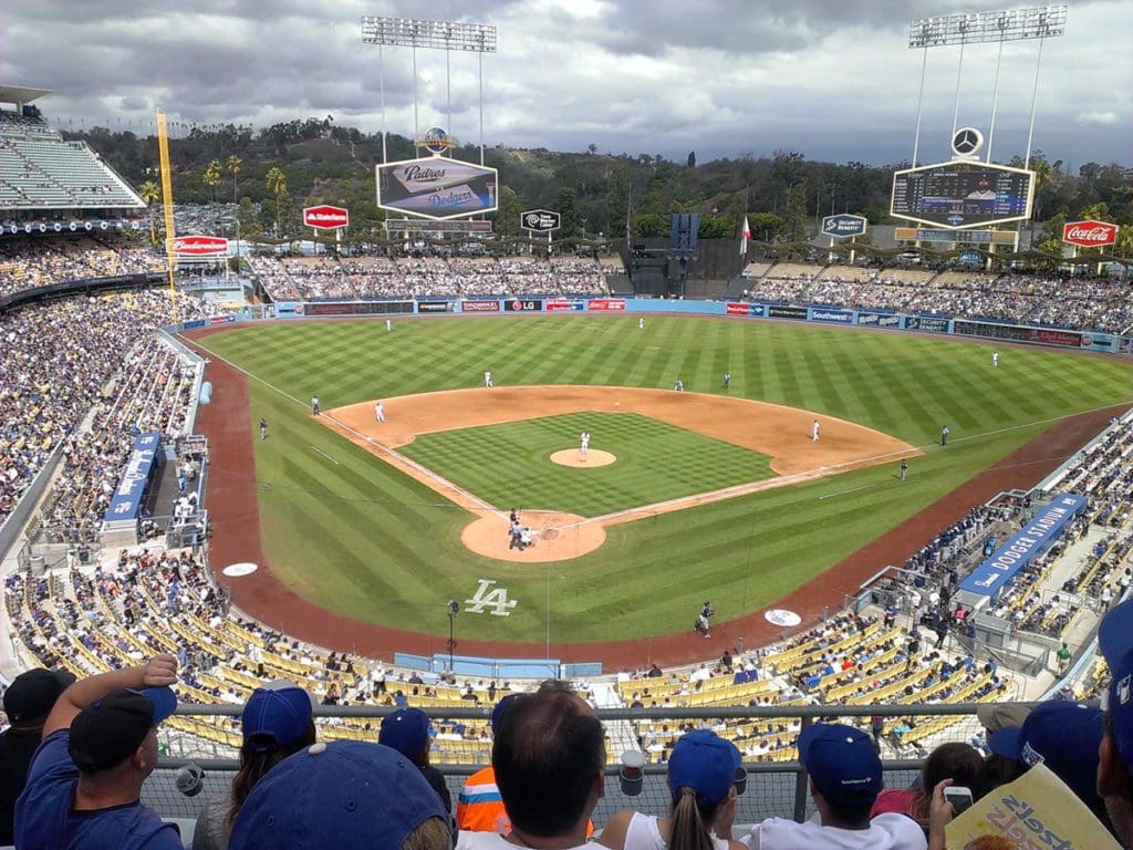 The field of Dodger Stadium behind rows of onlookers, while players fill their positions on the field.