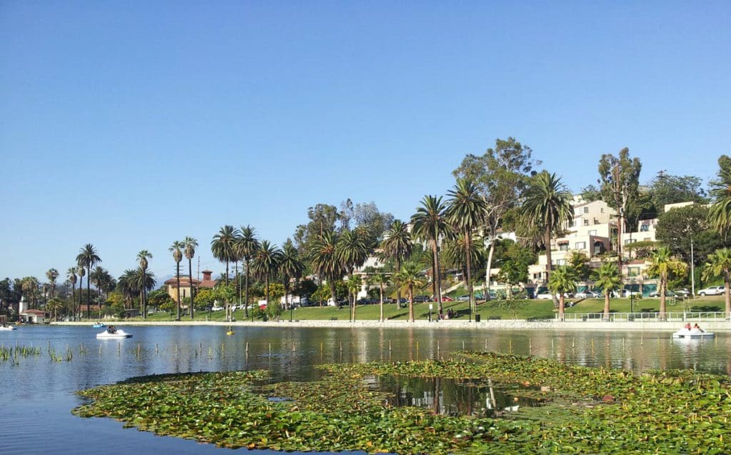 A view of Echo Park across the on-side pond, with green foliage and blue skies.