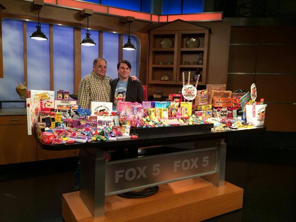 Two men standing in front a candy filled with various candy brands at Economy Candy Store, one of the best indoor New York City activities for kids.