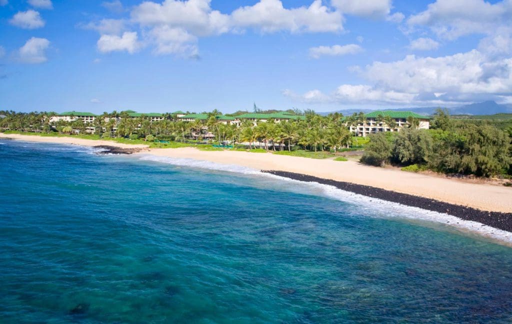 The long, stunning beach shore of Grand Hyatt Kauai Resort & Spa, featuring beautiful sand and blue waters.