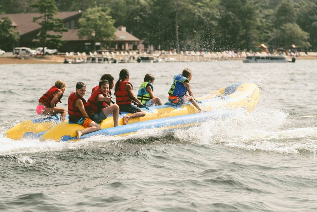 Several children ride on a banana boat tube pulled by a boat on the lake near Grand View Lodge Spa & Golf Resort.