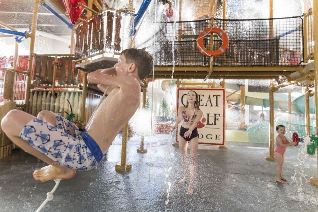 A young boy swings on a rope swing over the water in the indoor water park at Photo Courtesy: Great Wolf Lodge in the Wisconsin Dells.
