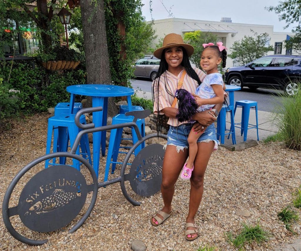 A mom holds her young daughter, both smiling, as they explore Atlanta, one of the best US cities for a Memorial Day Weekend with kids.