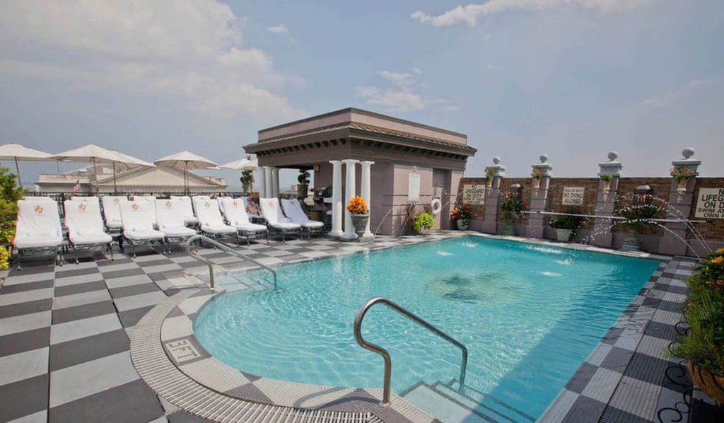 The outdoor pool at Market Pavilion Hotel, flanked by poolside loungers with shady umbrellas.