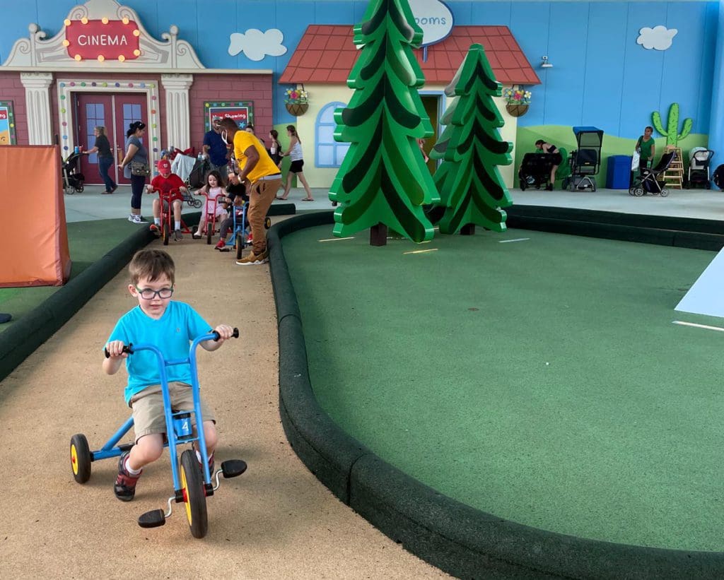 A young boy riding a tricycle races around a track at one of the play areas at the Peppa Pig Theme Park in Florida.