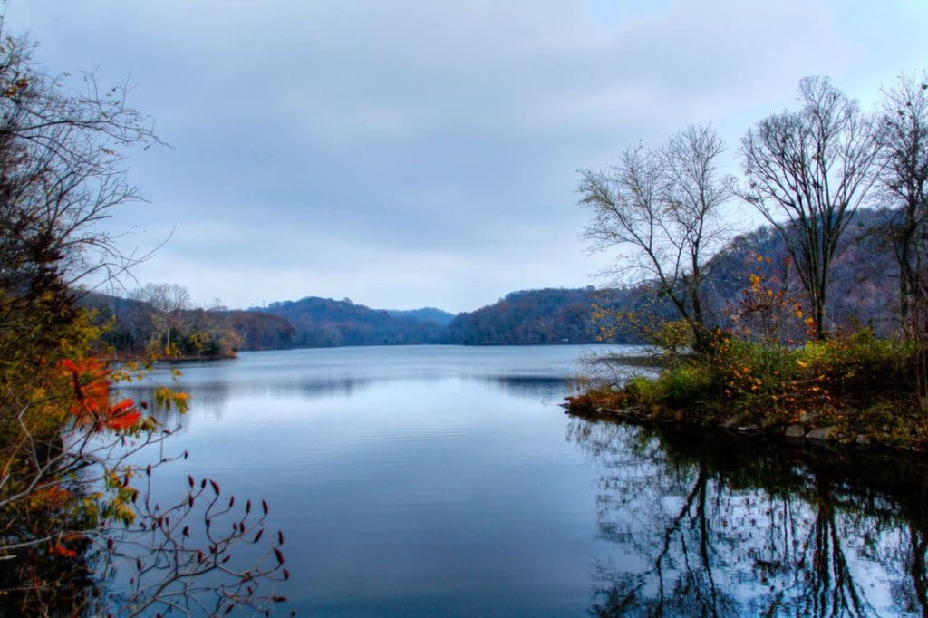A view of a beautiful lake, flanked by shorelines filled with trees in the fall, at Radnor Lake State Park.