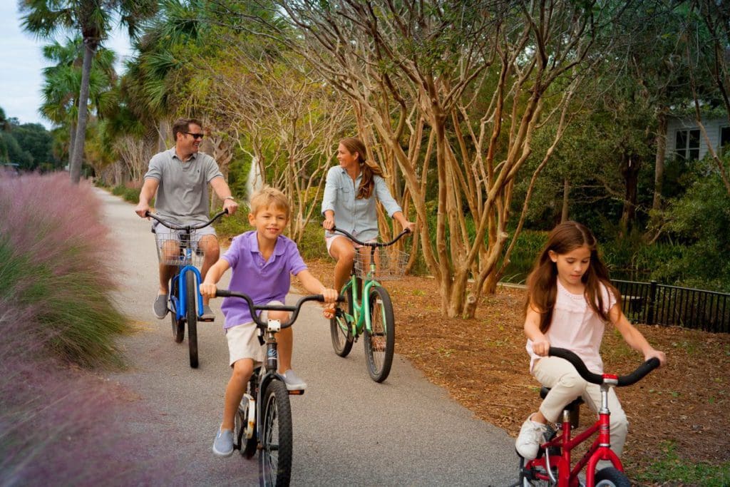 A family of four bikes along a peaceful, beachside path at Wild Dunes Resort.