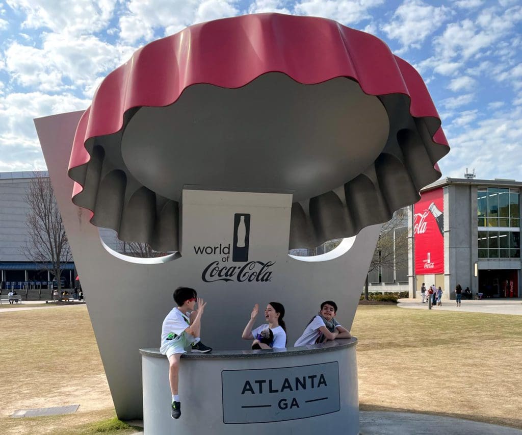 Three kids sit amongst the Coca-Cola statue outside Coca-Cola World in Atlanta.