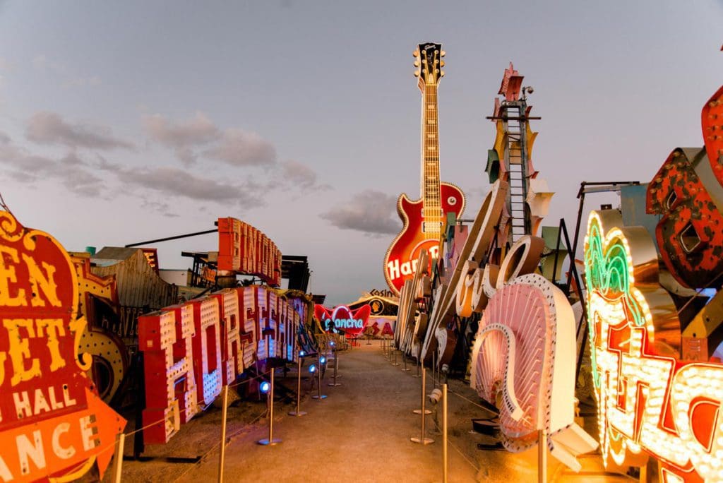 A view down one of the walkways at The Neon Museum, featuring huge neon signs on each side of the walkway.