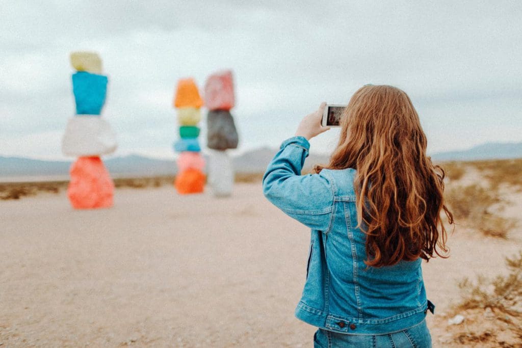A woman takes a picture of Seven Magic Mountains near Las Vegas, one of the best things to do in Las Vegas with kids.