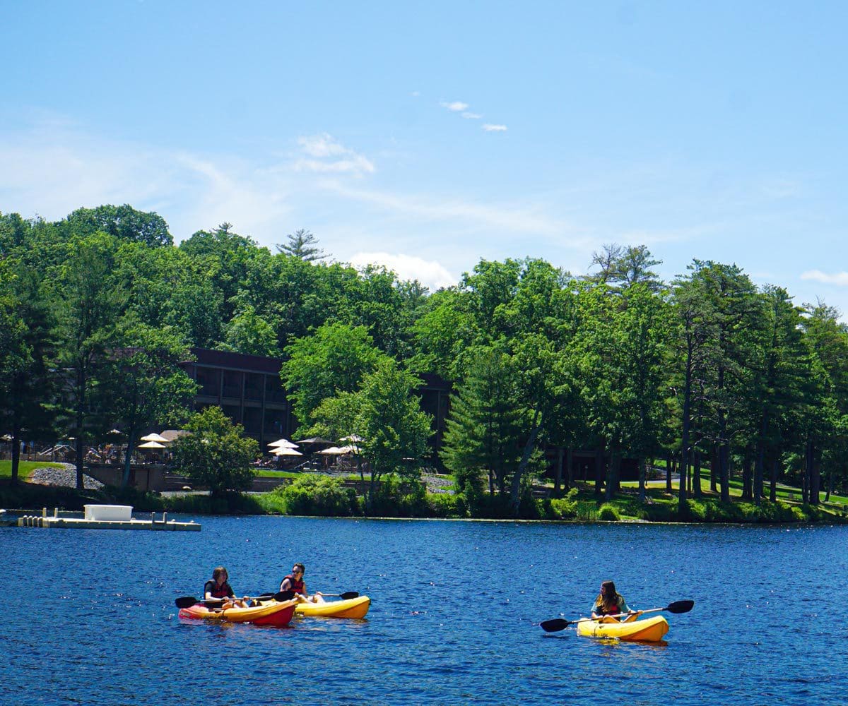 Three people kayaking in the lake at Woodloch Resort, one of the best all-inclusive hotels in the United States for families.