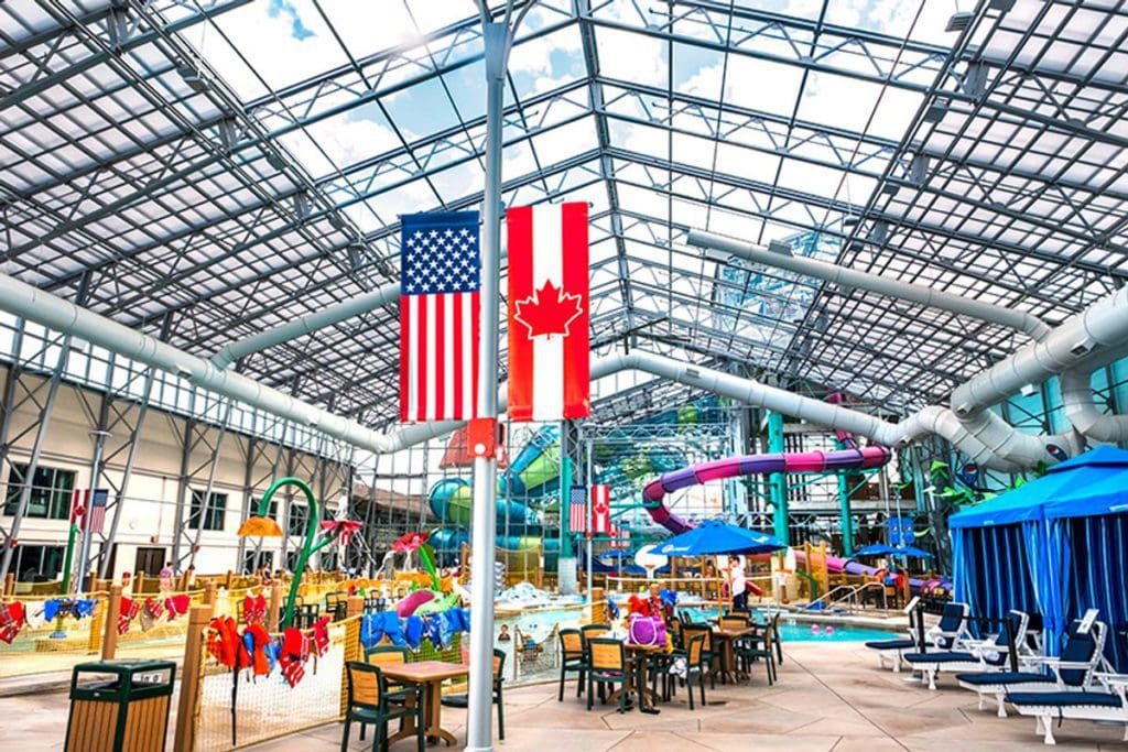 Inside the indoor waterpark of Zehnder’s Splash Village Hotel and Water Park, featuring an American and Canadian flag hanging in front of the slides and splash pads.