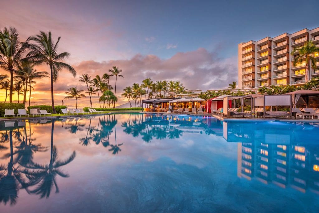 The pool at Andaz Maui at Wailea Resort - a Concept by Hyatt, with resort buildings in the background at sunset.