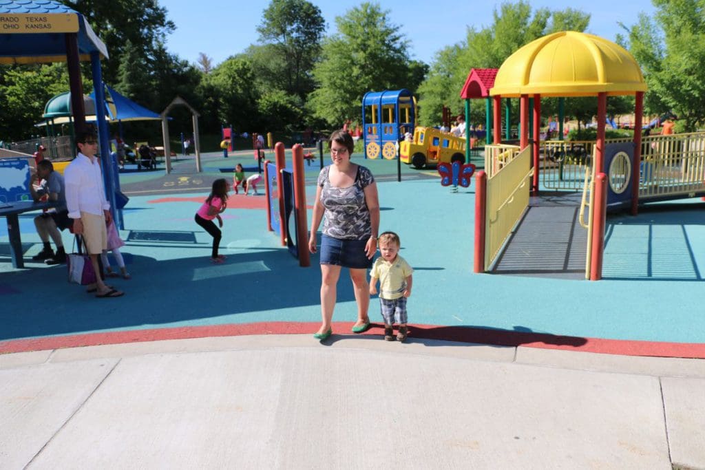 A mom and her young son walk across a colorful play area at Clemyjontri in DC.