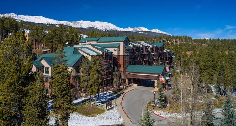 Hilton Grand Vacations Club Valdoro Mountain Lodge Breckenridge nestled amongst the pines with mountains in the distance at one of the best Hilton Hotels in the United States for families.