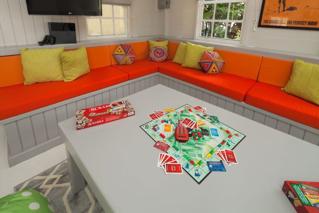 Inside the Teen Lounge at the Sugar Bay Barbados, featuring bright orange couches, and boardgames on the table.