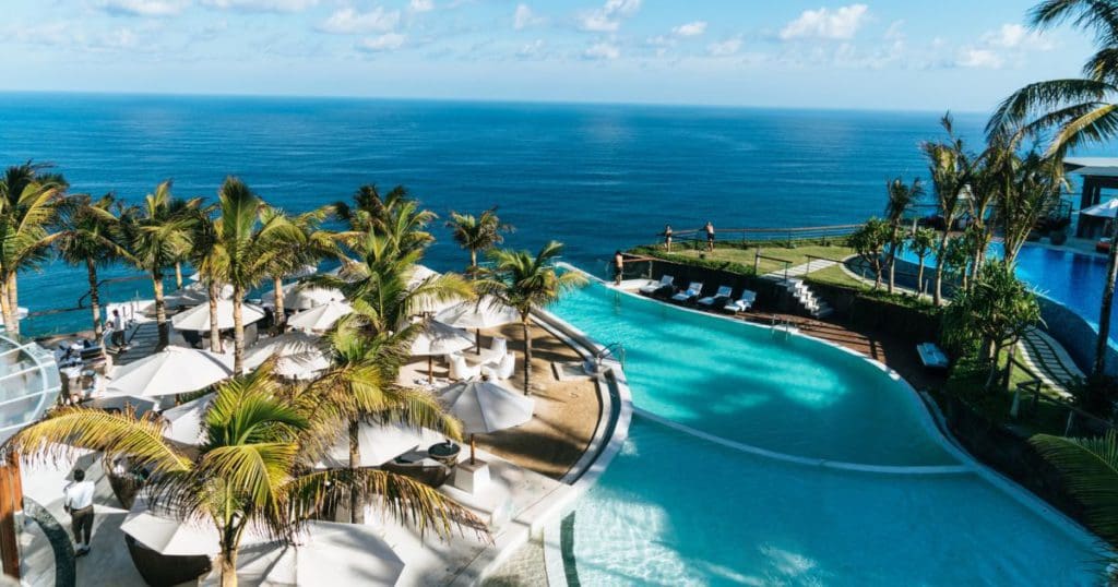 An aerial view of the large pool, circling the pool deck with loungers, with the ocean in the distance at Waldorf Astoria Monarch Beach Resort & Club.