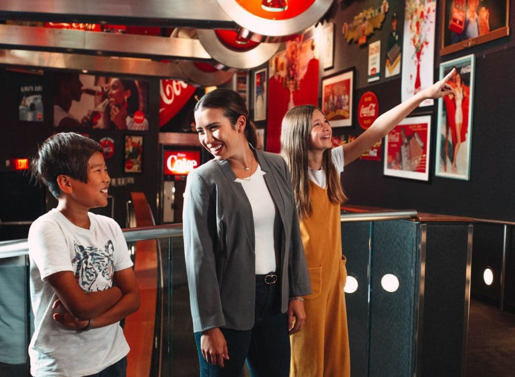 A mom and two kids enjoy the Coca-Cola inspired art inside World of Coca-Cola.