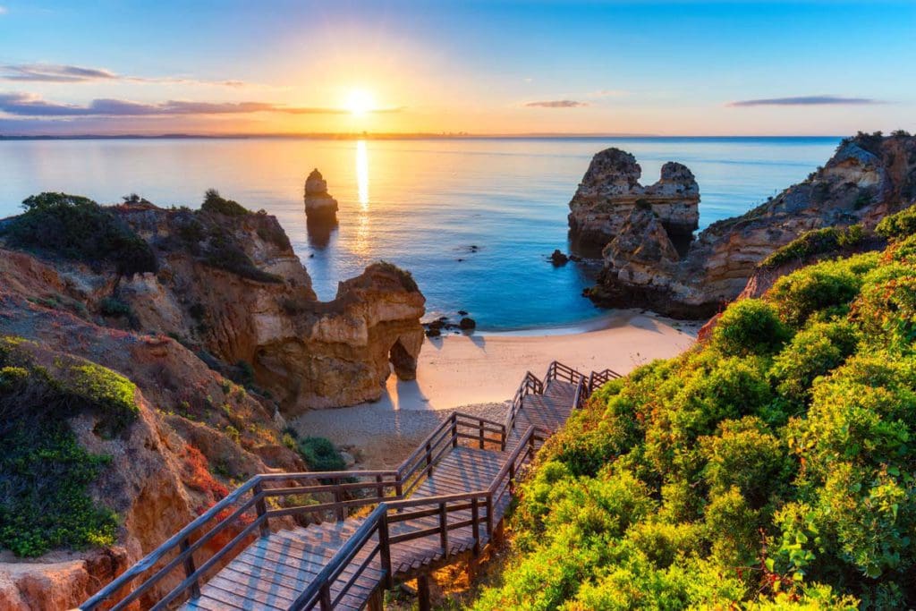 Camilo Beach at Algarve Portugal, flanked by a large rock formations at sunset.