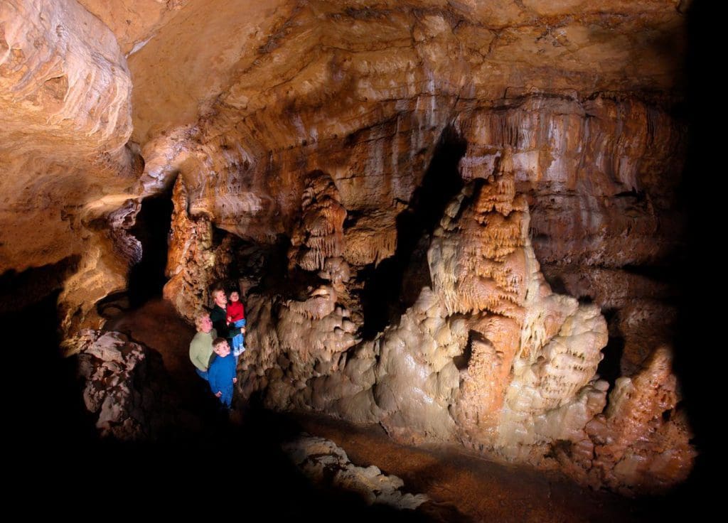 A family of four stands together admiring the cave features inside the Cave of the Mounds.