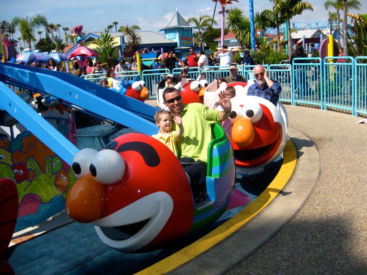 A dad and his toddler son enjoy a Elmo-themed ride at SeaWorld San Diego.