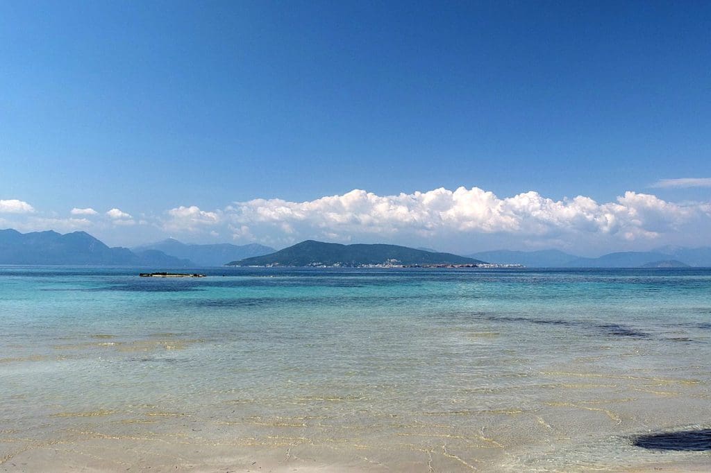 Crystal clear waters along Agistri Beach in Greece, with an island in the distance, one of the best beach destinations in Europe for families.