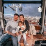 A family of three sits together and smiles in the Porto cable car.