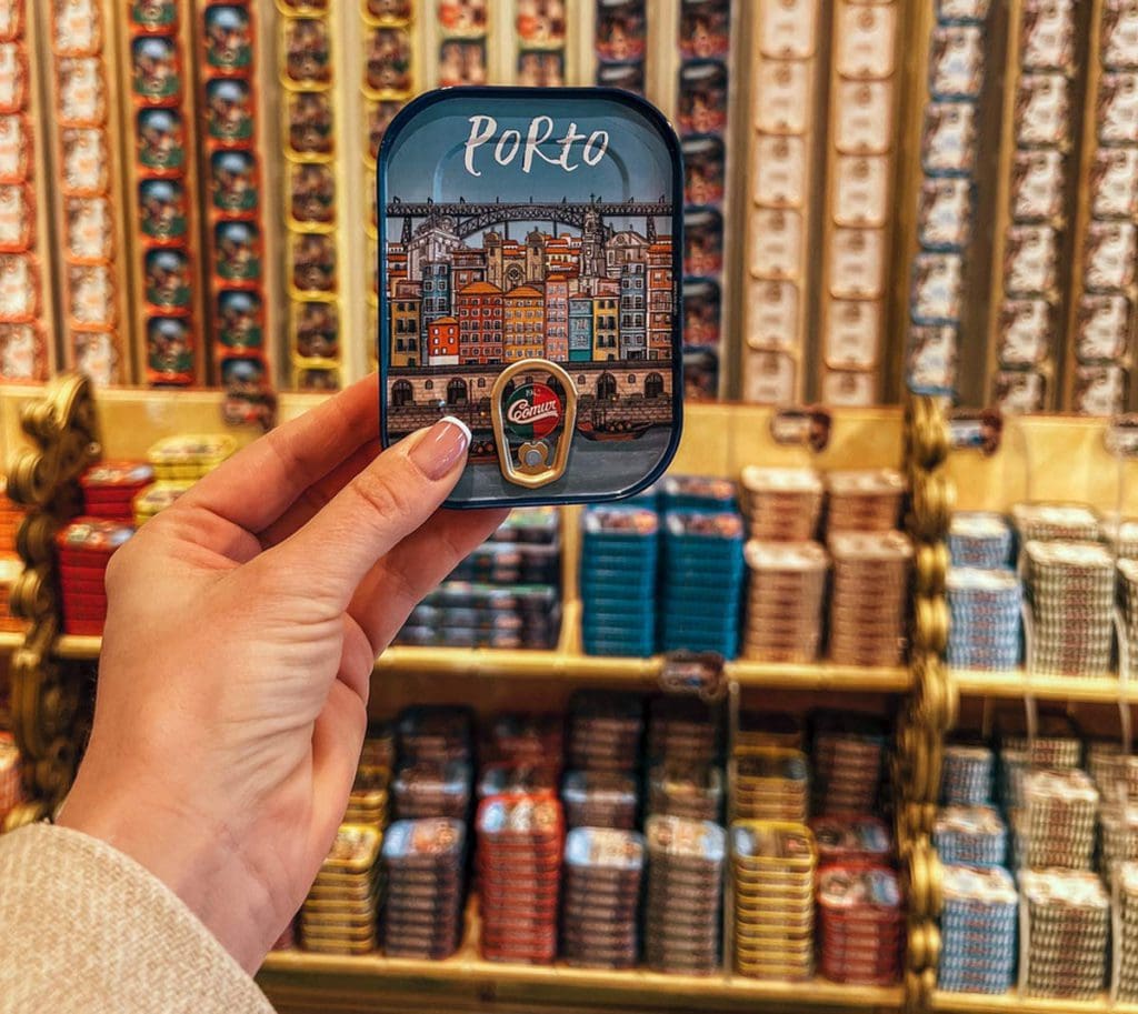 An outstretched hand holds a box reading "Porto" in a shop.