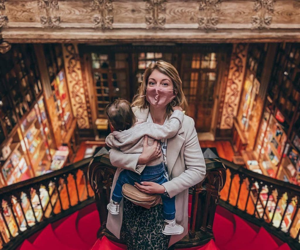 A young mom holds her toddler, while exploring a book store, a fun stop on our 1-Week Porto itinerary with toddlers.