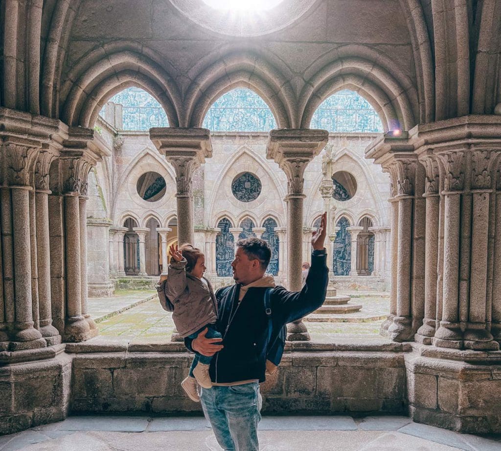 A dad holds his young daughter with large windows leading to a courtyard at Se Cathedral.