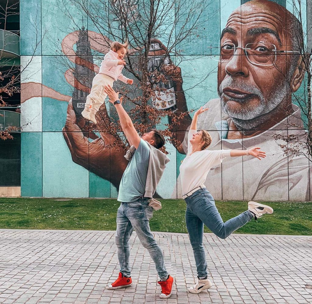 A dad throws his daughter playfully in the air, while mom watches on in Portugal.