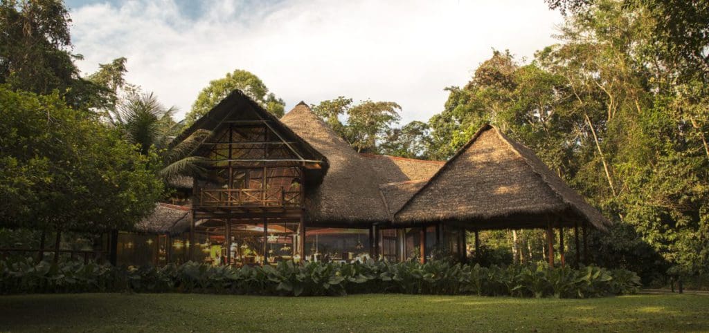 The large, rustic lodge building at Inkaterra Reserva Amazonica, surrounded by green trees.